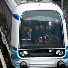 Eine Gruppe von Personen, darunter Politiker und Fotografen, in einem modernen Zug in Griechenland.