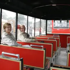 Ein älteres Paar genießt die Fahrt mit der Winterberg Bahn. Die roten Sitze und großen Fenster bieten einen tollen Ausblick.