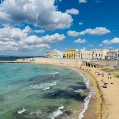 Sonne, Strand und Meer – ein gut mit Zug erreichbares Paradies. Türkisfarbenes Wasser trifft auf Sandstrand und weiße Häuser.