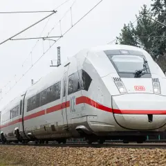 Moderner weißer ICE-Zug mit roten Streifen fährt auf Schienen. Eine Reise von Berlin nach Polen beginnt.