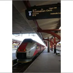 Moderner Zug am Bahnsteig, Anzeigetafel zeigt "Trollhättan Oslo".