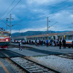 Roter und gelber **montenegro train** am Bahnhof, Menschen steigen ein und aus.