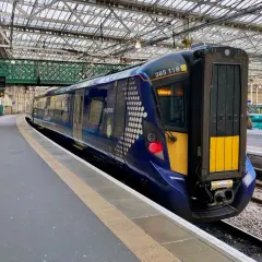 Ein moderner blauer Zug mit der Aufschrift "Edinburgh" steht bereit für die Abfahrt.