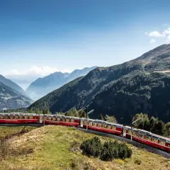 Der Bernina Express schlängelt sich **mit dem Zug durch die Schweiz** durch eine atemberaubende Berglandschaft.