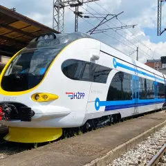Moderner weiß-blauer kroatischer Zug (HŽPP) steht am Bahnsteig.