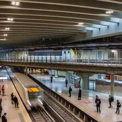 Moderne Züge fahren auf mehreren Ebenen im Brüsseler Bahnhof ein und aus. Reisende warten auf den Bahnsteigen.