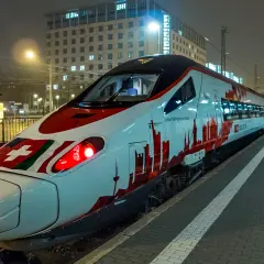 Moderner EC train in Deutschland mit Schweizer Flagge und Skyline-Design.