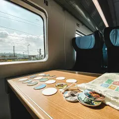 Blick aus dem Fenster eines **denmark train** mit vielen Untersetzern auf dem Tisch. Die Reise beginnt!