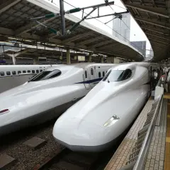 Zwei weiße Shinkansen-Züge stehen nebeneinander auf einem Bahnhof. Sie sind ein Symbol für die effizienten Zugverbindungen Japans.