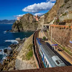 Zug fährt entlang der Küste von Manarola, ein malerischer Teil der Cinque Terre. Die Zugfahrt von Mailand hierher ist atemberaubend.