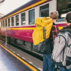 Zwei Rucksacktouristen warten am Bahnsteig auf ihren Zug. Die Reise beginnt, ein internationales Abenteuer.