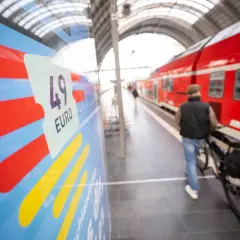 Mann mit Fahrrad am Bahnsteig, bereit für die Fahrt von Deutschland in die Niederlande. Das 49-Euro-Ticket ist im Fokus.