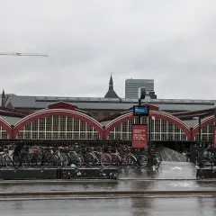 Fahrräder vor dem historischen Hauptbahnhof Kopenhagen. Ein Kran ragt in den grauen Himmel.