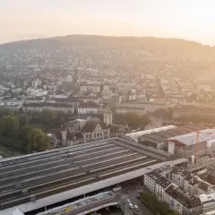 Luftaufnahme des Hauptbahnhofs Zürich bei Sonnenuntergang. Die vielen Gleise deuten darauf hin, welcher Bahnhof die meisten Gleise hat.
