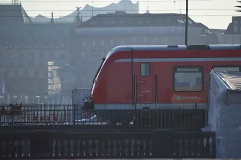 Roter Zug der Bahn Hamburg fährt durch die Stadt. Eine Reise mit dem Zug durch Deutschland beginnt hier.