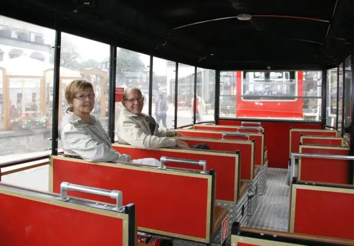 Ein älteres Paar genießt die Fahrt mit der Winterberg Bahn. Die roten Sitze und großen Fenster bieten einen tollen Ausblick.