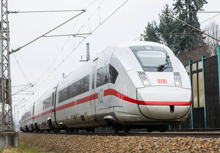 Moderner weißer ICE-Zug mit roten Streifen fährt auf Schienen. Eine Reise von Berlin nach Polen beginnt.