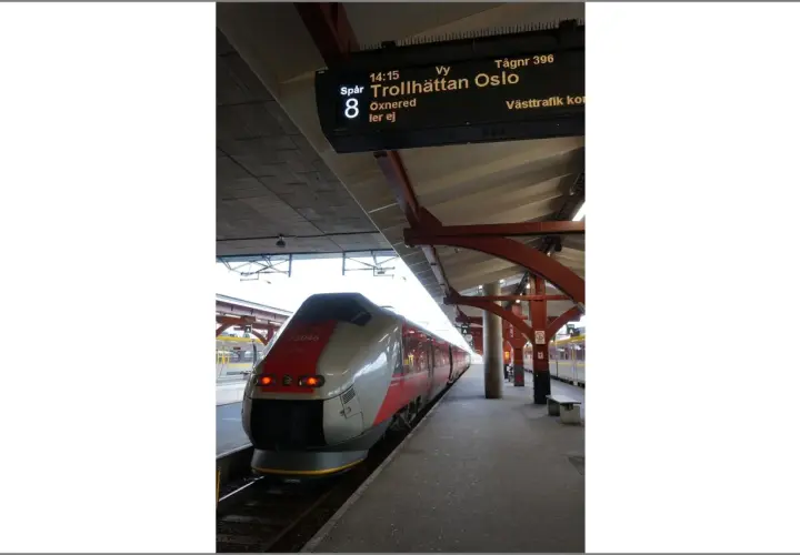 Moderner Zug am Bahnsteig, Anzeigetafel zeigt "Trollhättan Oslo".