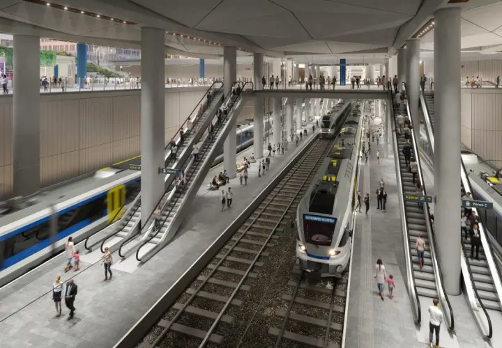 Moderne unterirdische Bahnhofshalle in Budapest mit Zügen, Rolltreppen und vielen Reisenden.