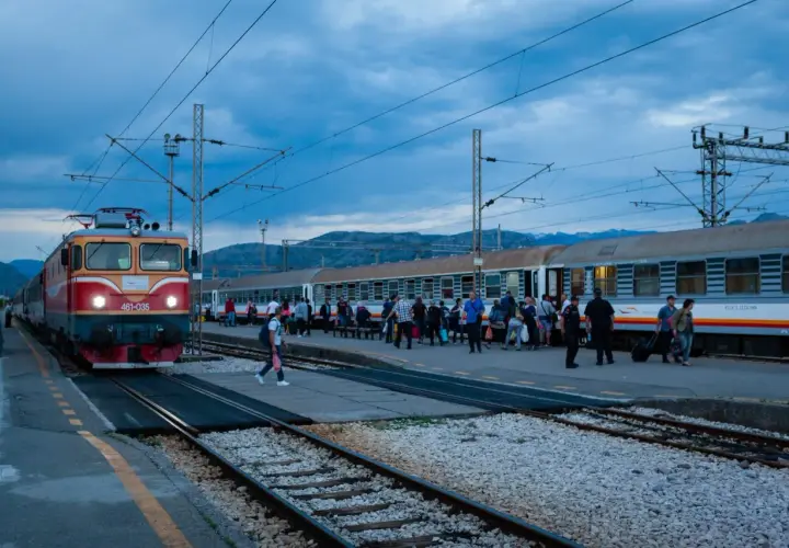 Roter und gelber **montenegro train** am Bahnhof, Menschen steigen ein und aus.