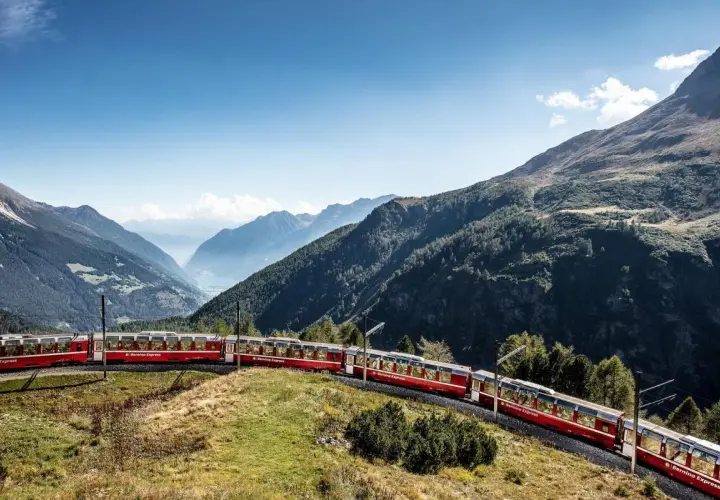 Der Bernina Express schlängelt sich **mit dem Zug durch die Schweiz** durch eine atemberaubende Berglandschaft.