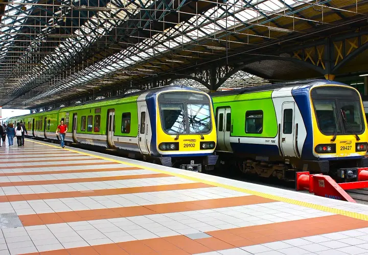 Zwei grüne und blaue Züge stehen auf einem Bahnsteig unter einem großen Dach.