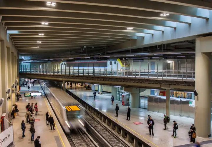 Moderne Züge fahren auf mehreren Ebenen im Brüsseler Bahnhof ein und aus. Reisende warten auf den Bahnsteigen.