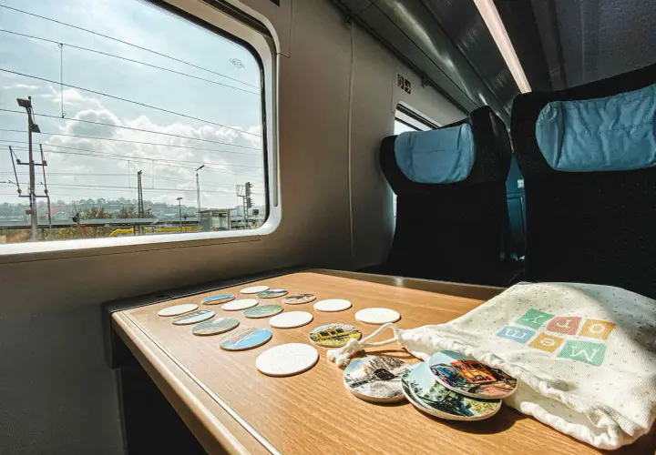 Blick aus dem Fenster eines **denmark train** mit vielen Untersetzern auf dem Tisch. Die Reise beginnt!
