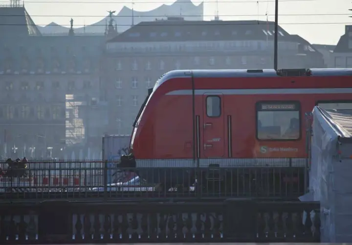 Roter Zug der Bahn Hamburg fährt durch die Stadt. Eine Reise mit dem Zug durch Deutschland beginnt hier.