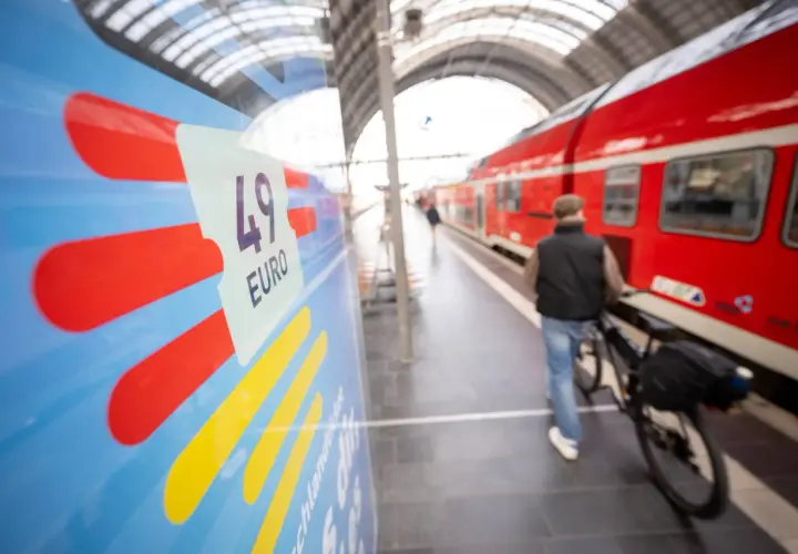 Mann mit Fahrrad am Bahnsteig, bereit für die Fahrt von Deutschland in die Niederlande. Das 49-Euro-Ticket ist im Fokus.
