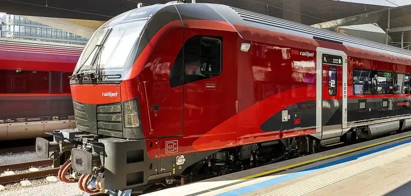 Roter Railjet Express Zug steht am Bahnsteig.