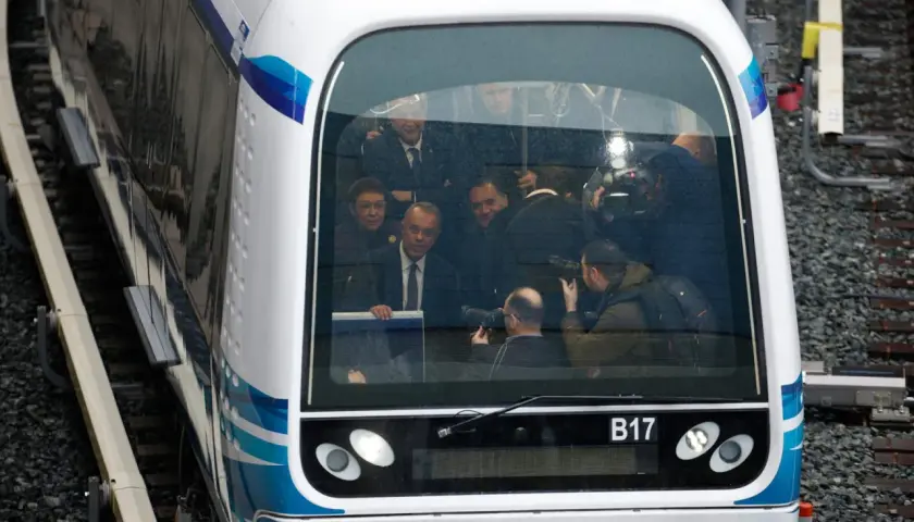 Eine Gruppe von Personen, darunter Politiker und Fotografen, in einem modernen Zug in Griechenland.