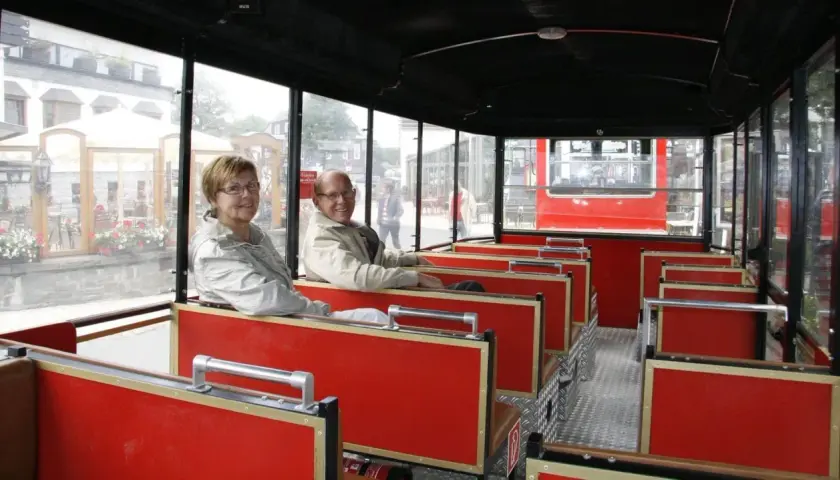 Ein älteres Paar genießt die Fahrt mit der Winterberg Bahn. Die roten Sitze und großen Fenster bieten einen tollen Ausblick.