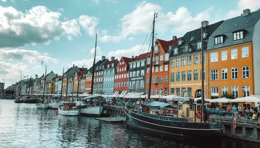 Bunte Häuser am Nyhavn-Kanal in Kopenhagen, Dänemark. Boote liegen im Wasser, ein perfekter Ort nach der **train to Copenhagen**.