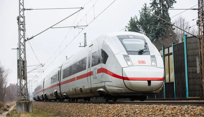 Moderner weißer ICE-Zug mit roten Streifen fährt auf Schienen. Eine Reise von Berlin nach Polen beginnt.