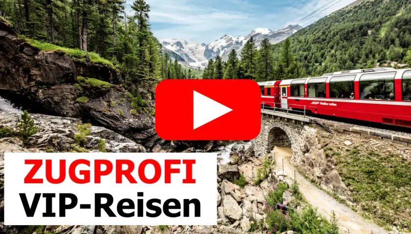 Roter Zug fährt über eine Steinbrücke durch eine Berglandschaft mit Wasserfall. Einer der besten landschaftlichen Zugfahrten.