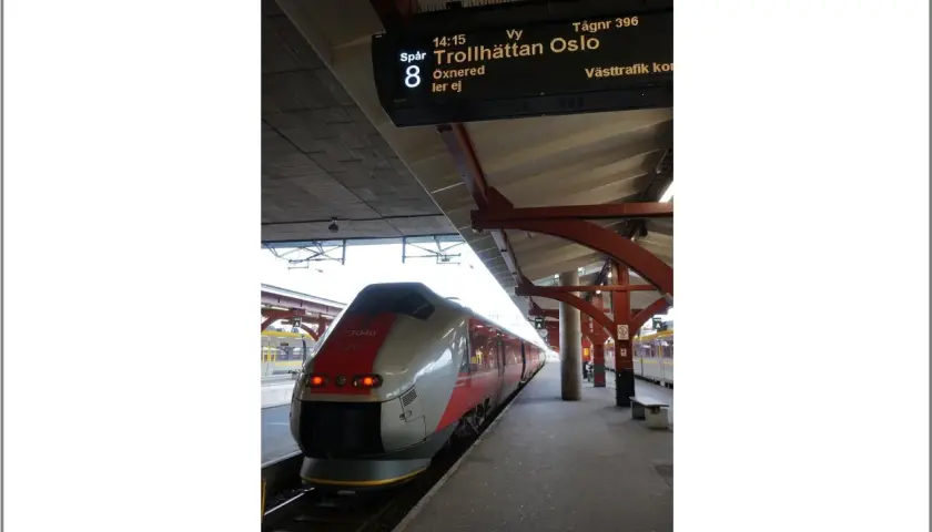 Moderner Zug am Bahnsteig, Anzeigetafel zeigt "Trollhättan Oslo".
