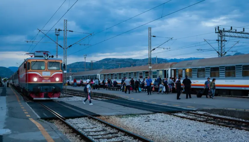 Roter und gelber **montenegro train** am Bahnhof, Menschen steigen ein und aus.