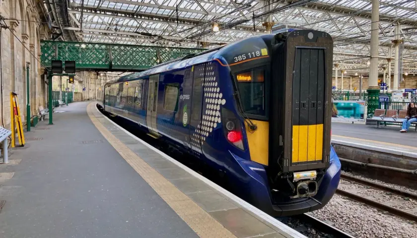 Ein moderner blauer Zug mit der Aufschrift "Edinburgh" steht bereit für die Abfahrt.