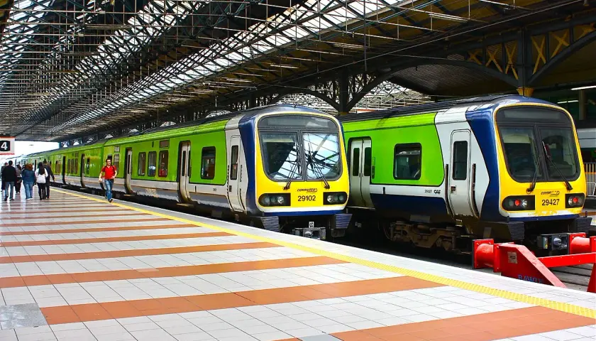 Zwei grüne und blaue Züge stehen auf einem Bahnsteig unter einem großen Dach.