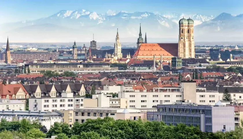Blick auf München mit Alpen im Hintergrund. Die Zugfahrt von Köln nach München ist eine Reise durch Deutschland.
