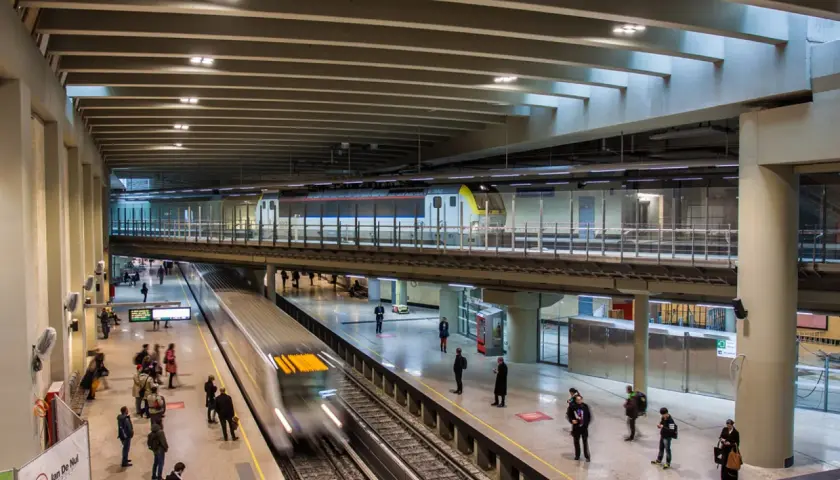 Moderne Züge fahren auf mehreren Ebenen im Brüsseler Bahnhof ein und aus. Reisende warten auf den Bahnsteigen.