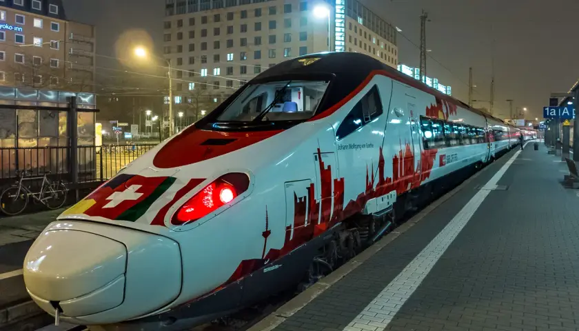 Moderner EC train in Deutschland mit Schweizer Flagge und Skyline-Design.