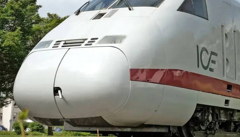 Der weiße ICE-Zug, ein deutscher Hochgeschwindigkeitszug, steht auf Gleisen im Gras.