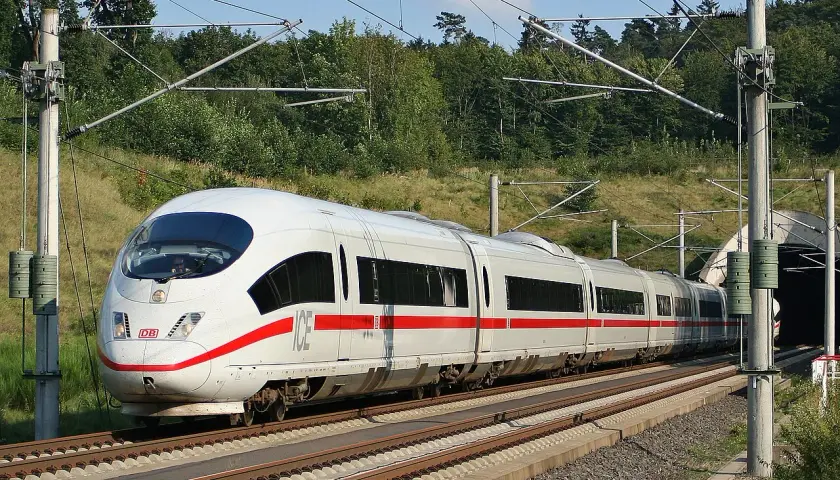 Ein weißer ICE mit roten Streifen fährt auf den Gleisen Richtung Tunnel. Die Fahrt von Frankfurt nach Basel beginnt.