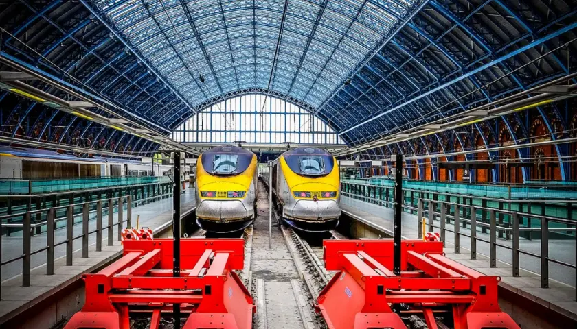 Zwei gelbe Eurostar-Züge stehen bereit für die Fahrt von Paris nach London unter dem beeindruckenden Glasdach des Bahnhofs.