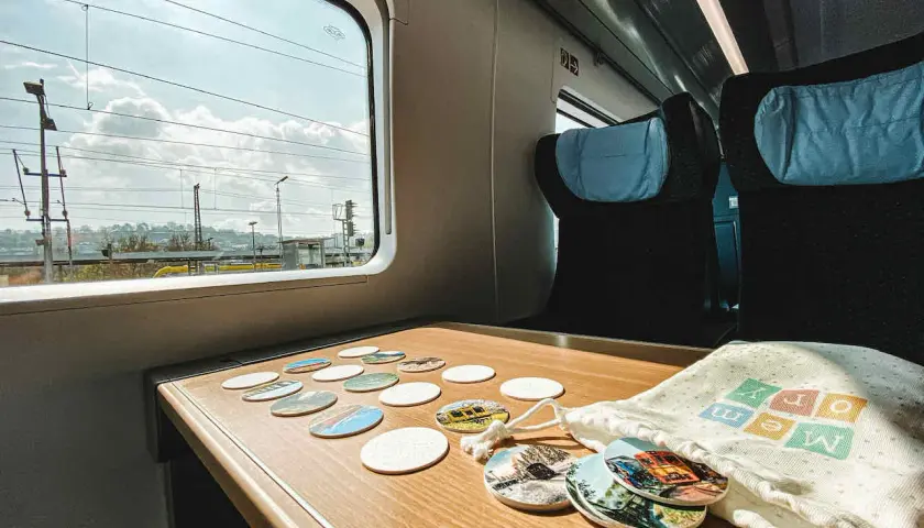 Blick aus dem Fenster eines **denmark train** mit vielen Untersetzern auf dem Tisch. Die Reise beginnt!