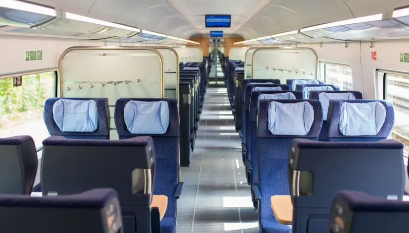 Leere Sitze in einem modernen Zugabteil. Die blauen Polster mit hellblauen Kopfkissen laden zur entspannten train ride ein.