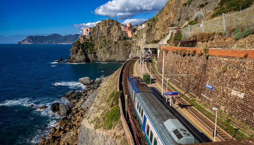 Zug fährt entlang der Küste von Manarola, ein malerischer Teil der Cinque Terre. Die Zugfahrt von Mailand hierher ist atemberaubend.