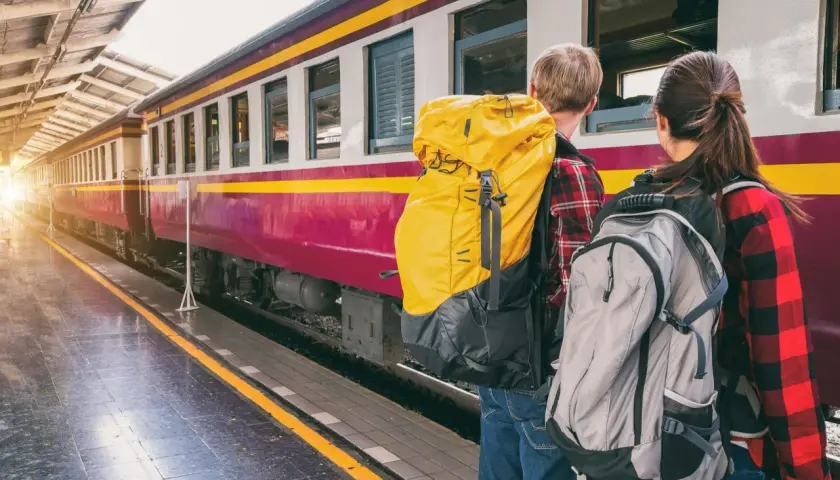 Zwei Rucksacktouristen warten am Bahnsteig auf ihren Zug. Die Reise beginnt, ein internationales Abenteuer.